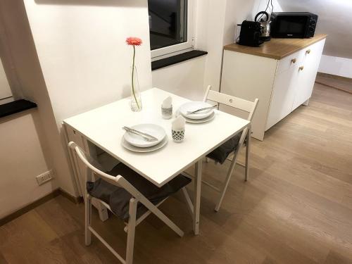 a white table and chairs with a vase with a flower on it at La Finestra Sull’Oasi in Genova