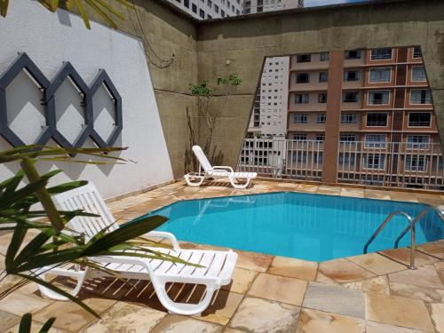 a swimming pool with two chairs next to a building at Hotel Elo Curitiba in Curitiba