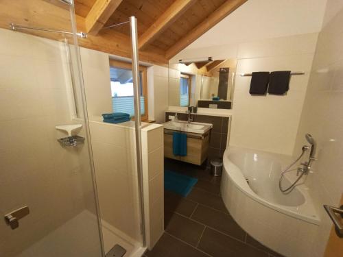 La salle de bains est pourvue d'une douche, d'une baignoire et d'un lavabo. dans l'établissement Ferienwohnung Abendsonne, à Oy-Mittelberg