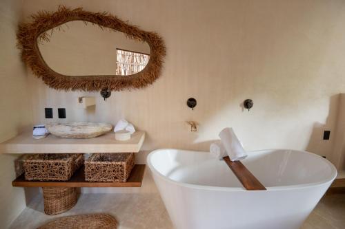 La salle de bains est pourvue d'une grande baignoire blanche et d'un miroir. dans l'établissement Rubi Tulum, à Tulum