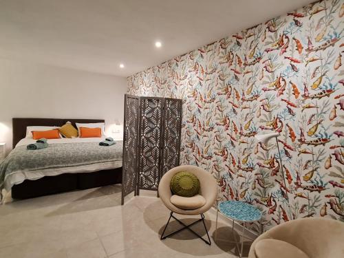 ein Schlafzimmer mit einem Bett, einem Stuhl und einer Wand in der Unterkunft Suites in Ca Olivar, Moraira in Teulada
