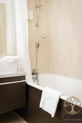 a bathroom with a bath tub and a sink at Adonis Gapotel in Gap
