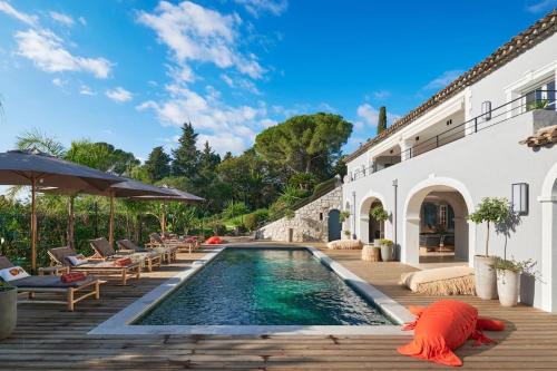 - une piscine avec des chaises et des parasols à côté d'une maison dans l'établissement Cannes magnifique villa vue mer basse Californie, à Cannes