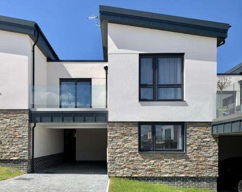 a white house with black windows and a driveway at Tolcarne - Perranporth Cornwall in Perranporth