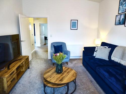 a living room with a blue couch and a table at Tolcarne - Perranporth Cornwall in Perranporth