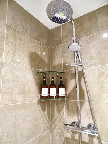 a shower with three bottles of wine on a shelf at Tolcarne - Perranporth Cornwall in Perranporth