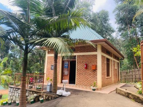 une petite maison avec un palmier en face dans l'établissement EAR KEN BARHAM GUESTHOUSE, à Rwumba