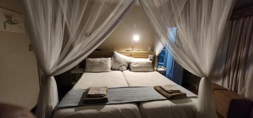 a bedroom with a bed with white drapes at Kiaat Bungalows in Hazyview