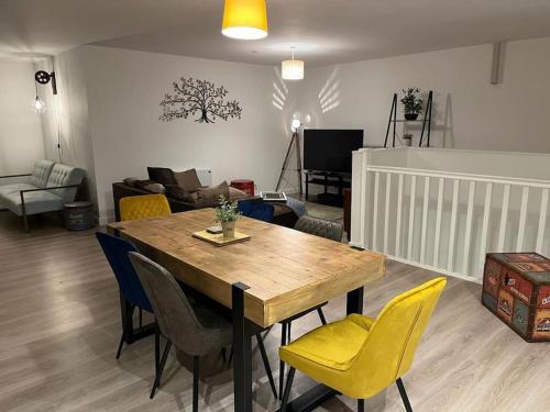a living room with a wooden table and yellow chairs at Bayard Luxe 2 Bedroom Penthouse Duplex in Peterborough