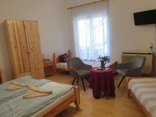 エゲルにあるFőnix Panzióのベッドルーム1室(ベッド2台、テーブル、椅子付)