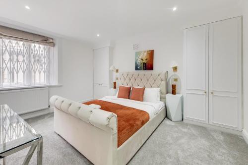 a white bedroom with a large bed and a window at The Belgravia Residences in London