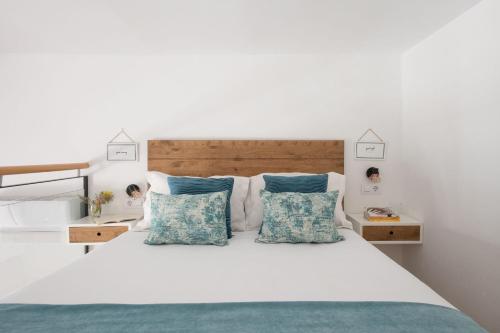 een slaapkamer met een wit bed met blauwe kussens bij Capricho de Quevedo in Sevilla