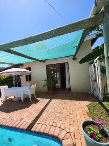 eine Terrasse mit einem Tisch und einem Sonnenschirm neben einem Haus in der Unterkunft Guesthouse Private Room with Garden and Pool in Gaborone