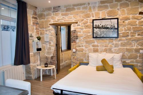 une chambre avec un lit et un mur en pierre dans l'établissement Sweet Virtue-Center of Paris, 2 Bedroom apartment, à Paris
