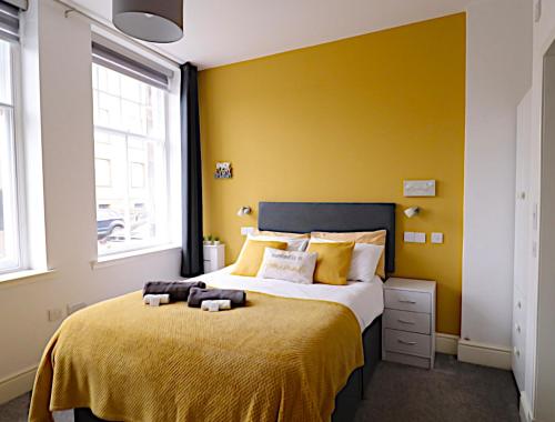 um quarto com uma cama grande e paredes amarelas em Double Ensuite Bedroom near Edinburgh em Kirkcaldy