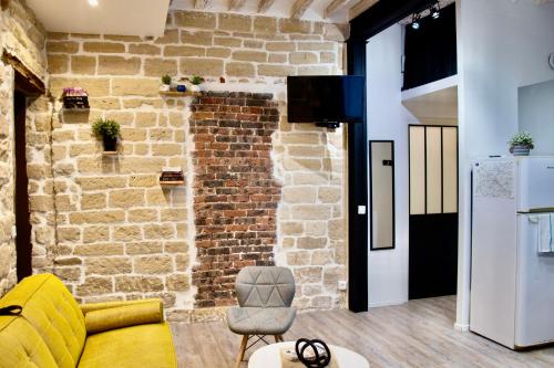 - un salon avec un canapé jaune et un mur en briques dans l'établissement Sweet Virtue-Center of Paris, 2 Bedroom apartment, à Paris