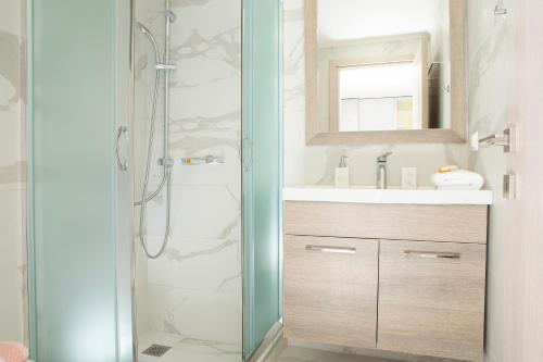 a bathroom with a shower and a sink and a mirror at PANTHEON RESORT AND VILLAS in Agios Nikitas