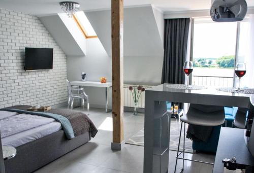 Schlafzimmer mit einem Bett und einem Tisch mit einem Glas Wein in der Unterkunft Apartamenty Na Skarpie in Lyck