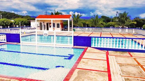 una gran piscina con una casa en el fondo en Acogedora casa condominio con piscina en Girardot, en Girardot