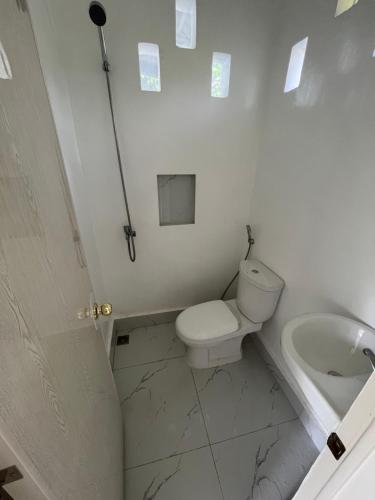 a white bathroom with a toilet and a sink at Vistapaloma beach resort in Odiong