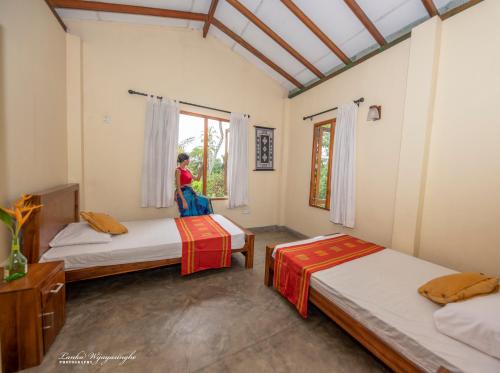 Eine Frau steht in einem Zimmer mit 2 Betten in der Unterkunft Tekkawatta in Colombo