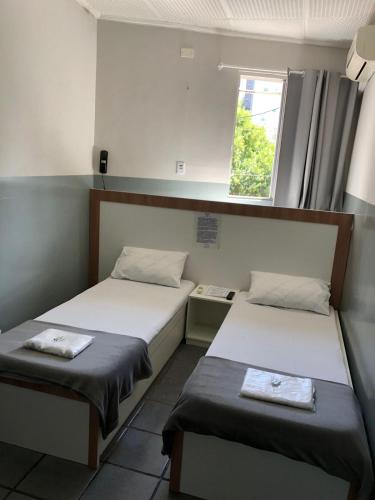 two beds in a small room with a window at Hotel Sany SP- Metrô Paulista in Sao Paulo