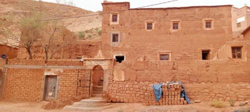 ein altes Backsteingebäude mit einer Tür und einer Tür in der Unterkunft Pergolas Tamakouchte in Ouarzazate