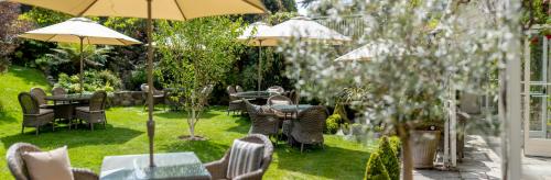 a garden with tables and chairs and umbrellas at The Royal Hotel in Ventnor