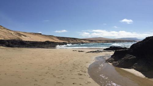 a beach with rocks and the ocean on a sunny day at Welooveyou Zafiro's in Morro del Jable