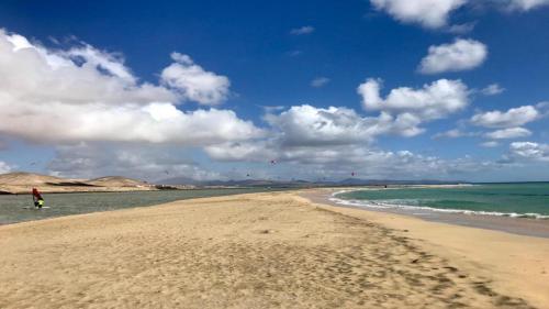 a person standing on a beach near the ocean at Welooveyou Zafiro's in Morro del Jable
