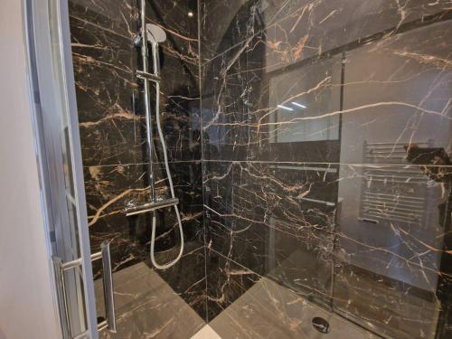 La salle de bains est pourvue d'une douche en marbre noir. dans l'établissement Gregbnb - T2 37m2 -1- Est -, à Toulon