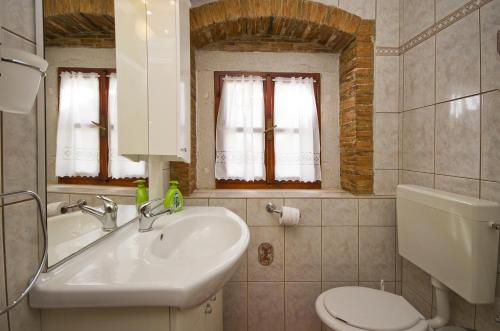 a bathroom with a sink and a toilet and windows at Mon Perin Castrum - Apartment Ivan in Bale