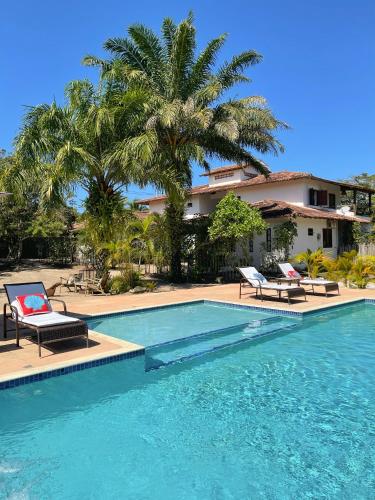 una piscina con 2 tumbonas y una casa en Pousada Suites Nativas, en Trancoso