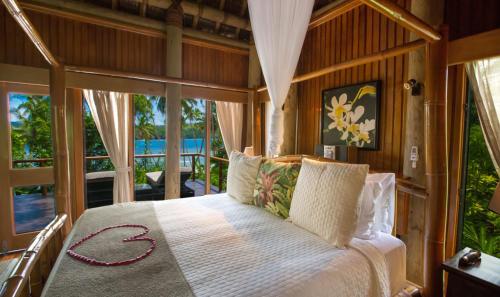 ein Schlafzimmer mit einem Bett in einem Zimmer mit Fenstern in der Unterkunft Namale All Inclusive Resort & Spa in Savusavu