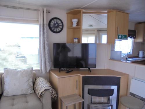 a living room with a couch and a large television at 6 Berth on Golden Anchor (Cascade) in Chapel Saint Leonards