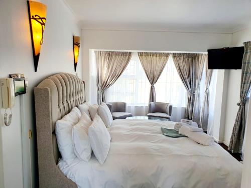 a bedroom with a large white bed with a couch at La Grace Executive Guesthouse in Amsterdamhoek