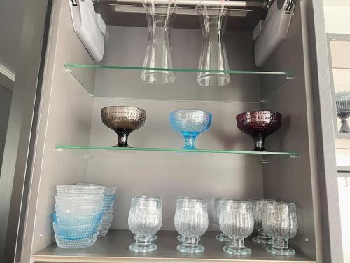 a rack of glasses and bowls on shelves in a refrigerator at Cozy & modern central-apartment in Turku