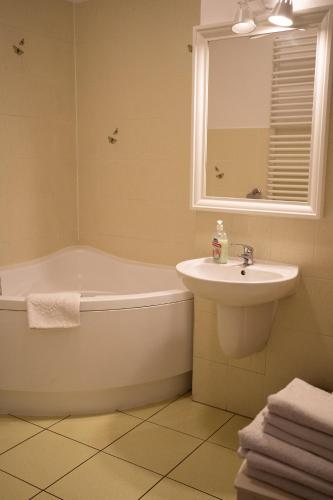クラクフにあるKolory Guest Houseの浴槽と洗面台とバスタブを備えたバスルーム