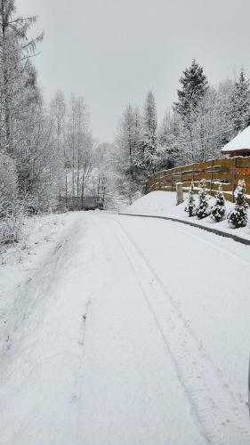 a snow covered road with a fence and trees at Osada Kuboski Dom z Bali Leśny Zakątek in Kamesznica
