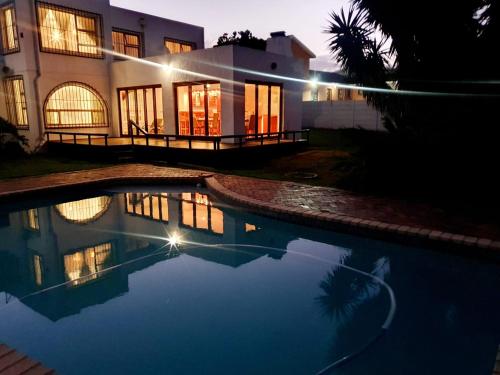 a house with a swimming pool at night at La Grace Executive Guesthouse in Amsterdamhoek