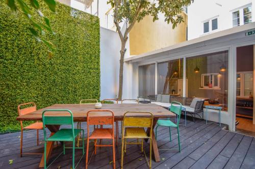 a wooden table with colorful chairs on a deck at The Lx Hill in Lisbon