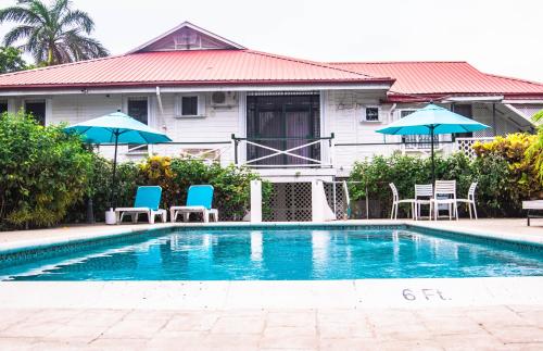 a swimming pool with chairs and umbrellas in front of a house at Harbour View Boutique Hotel & Wellness Retreat in Belize City