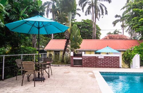 a table and chairs with an umbrella next to a pool at Harbour View Boutique Hotel & Wellness Retreat in Belize City