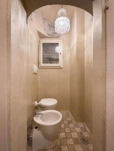 a bathroom with a white toilet and a chandelier at Renaissance Palace Noble Floor Apartment in Florence