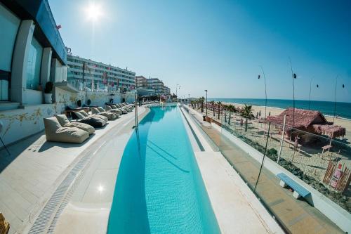 a swimming pool next to a beach with the ocean at ON Hotels Oceanfront Adults Designed in Matalascañas