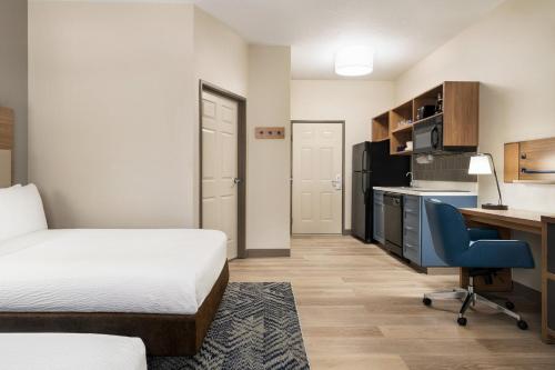 a hotel room with a bed and a desk and a kitchen at Candlewood Suites Boise-Meridian by IHG in Meridian