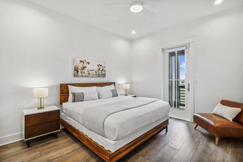 ein weißes Schlafzimmer mit einem großen Bett und einem Stuhl in der Unterkunft The Fairway Farmhouse in Port Aransas