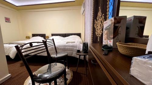 a bedroom with two beds and a table with two chairs at Ad Deir Guesthouse in Wadi Musa