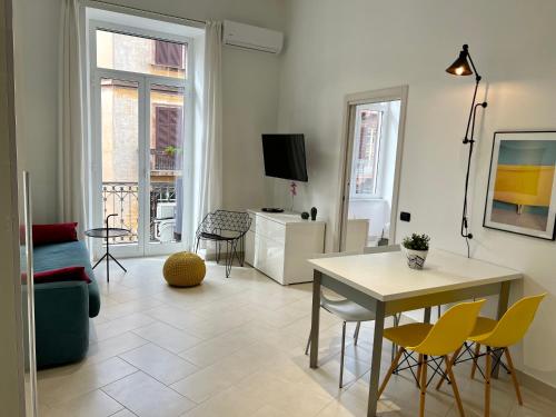 a living room with a table and yellow chairs at Duomo Inn Apartments in Naples