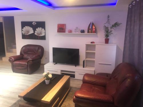 a living room with two leather chairs and a flat screen tv at Willa chez willi in Niederschaeffolsheim